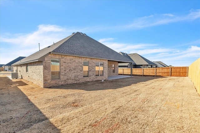 9213 NW 84th St, Yukon, OK 73099 - rear view of house featuring brick siding, central AC, a fenced backyard, and roof with shingles