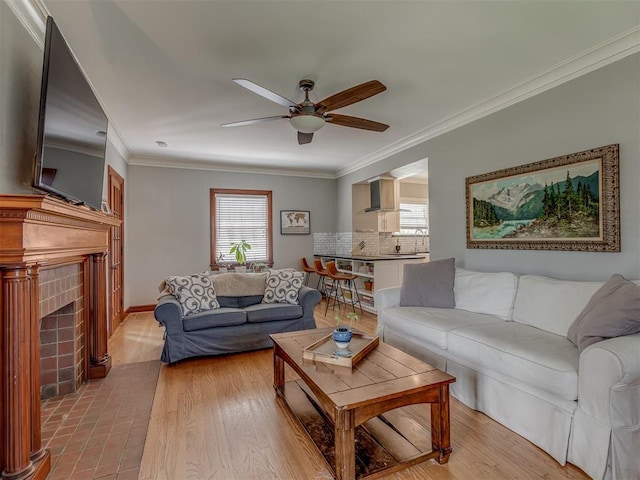 living room with a fireplace, a healthy amount of sunlight, a ceiling fan, and crown molding
