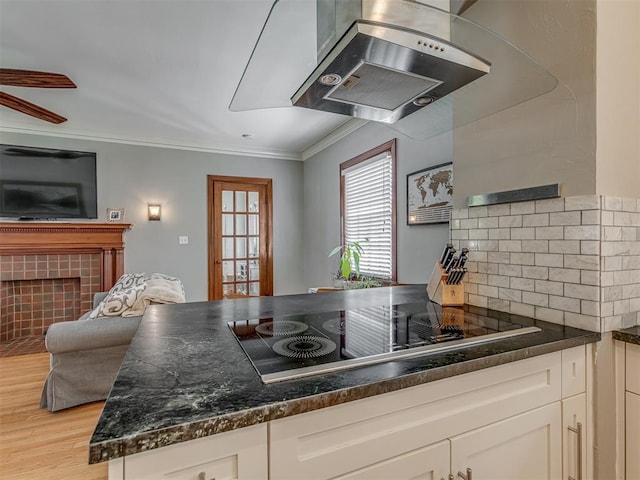 kitchen with wall chimney range hood, white cabinetry, crown molding, light wood-style flooring, and black electric cooktop