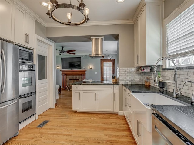 kitchen with ornamental molding, dark countertops, appliances with stainless steel finishes, and ceiling fan with notable chandelier