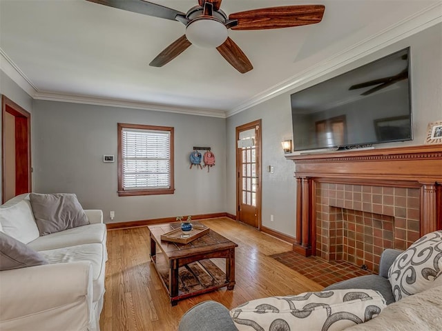 living area with crown molding, a ceiling fan, light wood-style flooring, and baseboards