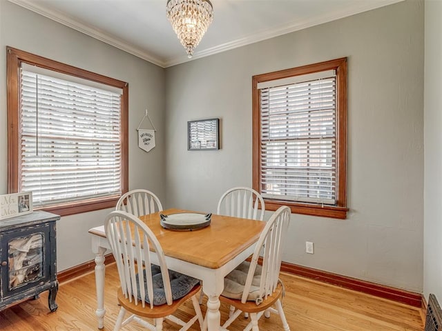 dining room with ornamental molding, a notable chandelier, light wood finished floors, and plenty of natural light