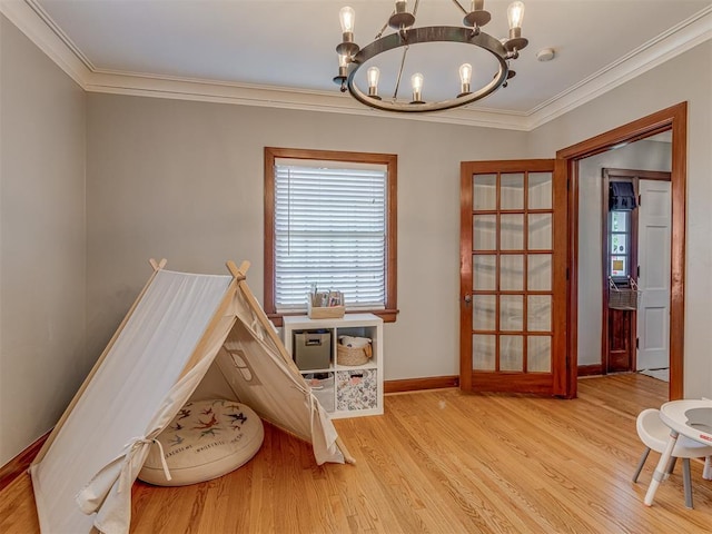 game room featuring ornamental molding, wood finished floors, a chandelier, and baseboards