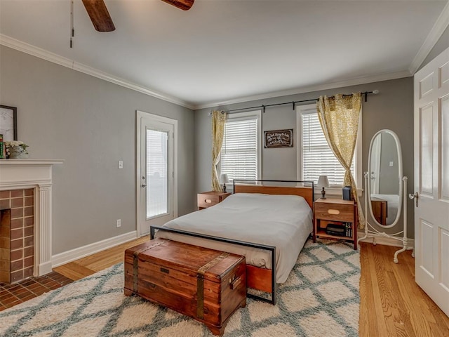 bedroom featuring a tile fireplace, light wood-type flooring, crown molding, a ceiling fan, and baseboards