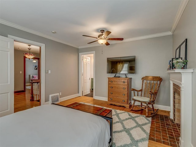 bedroom featuring wood finished floors, ornamental molding, baseboards, visible vents, and a ceiling fan