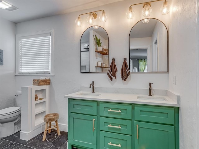 full bath with toilet, double vanity, a sink, and marble finish floor