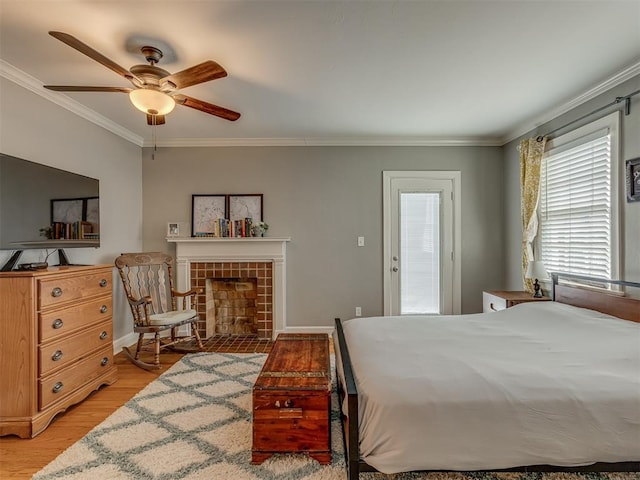 bedroom featuring light wood finished floors, a tile fireplace, a ceiling fan, baseboards, and ornamental molding
