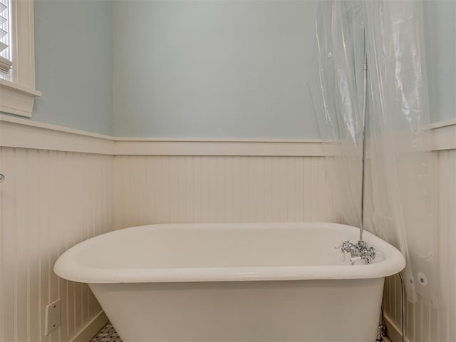 bathroom featuring a soaking tub and wainscoting
