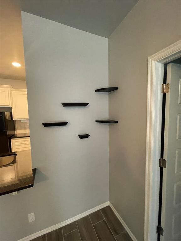 interior details featuring freestanding refrigerator, dark countertops, baseboards, wood finish floors, and white cabinets