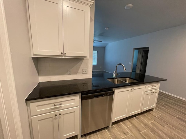 kitchen with stainless steel dishwasher, a sink, backsplash, and white cabinets