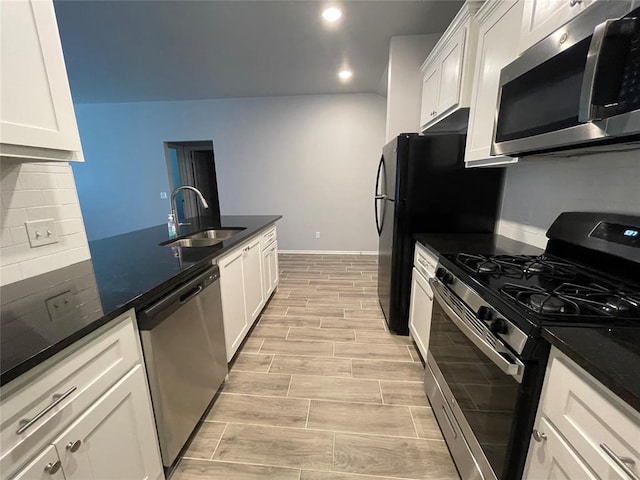 kitchen with a sink, appliances with stainless steel finishes, white cabinets, and light wood-style flooring