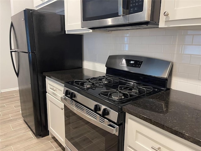 kitchen with wood tiled floor, dark stone countertops, white cabinets, and stainless steel appliances