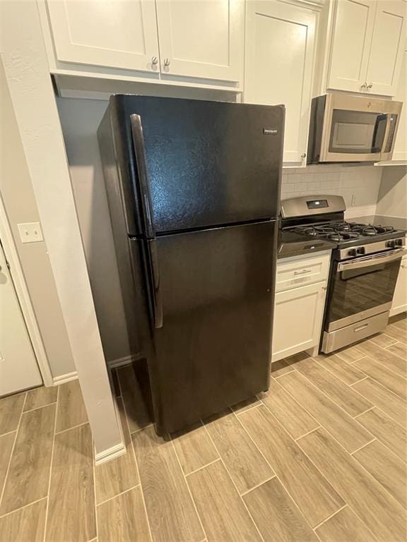 kitchen with white cabinets, stainless steel appliances, backsplash, and wood tiled floor