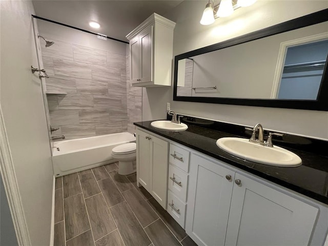 bathroom with a sink, wood tiled floor, toilet, and double vanity