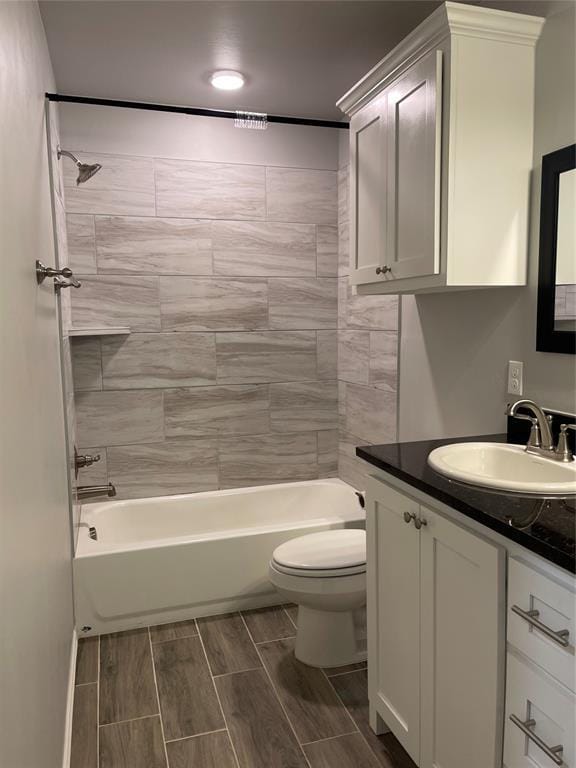 bathroom with vanity, wood finish floors, toilet, and shower / tub combination