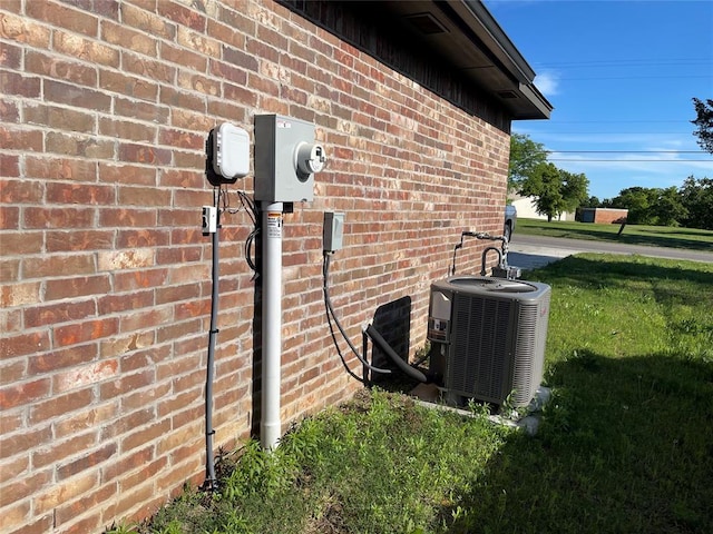 exterior details featuring electric meter, cooling unit, and brick siding