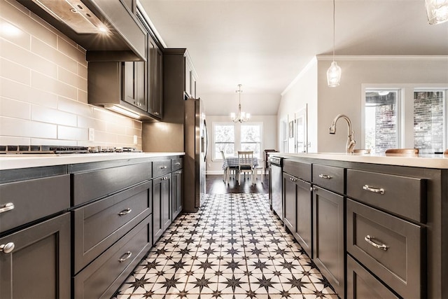 kitchen with a chandelier, stainless steel appliances, wall chimney exhaust hood, ornamental molding, and light floors