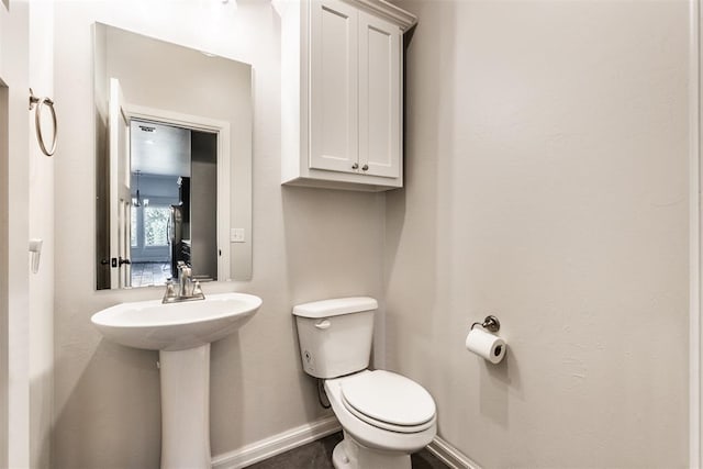 bathroom with baseboards, toilet, and a sink