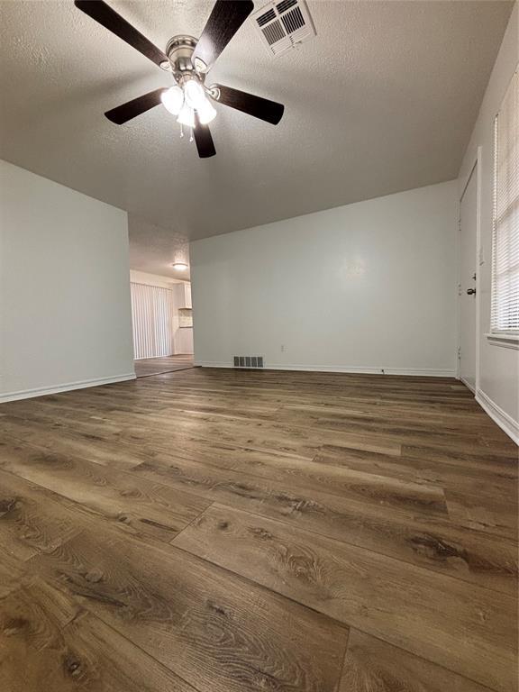 5213 Lombardy Ln, Oklahoma City, OK 73112 - spare room with dark wood-type flooring, a textured ceiling, ceiling fan, and baseboards