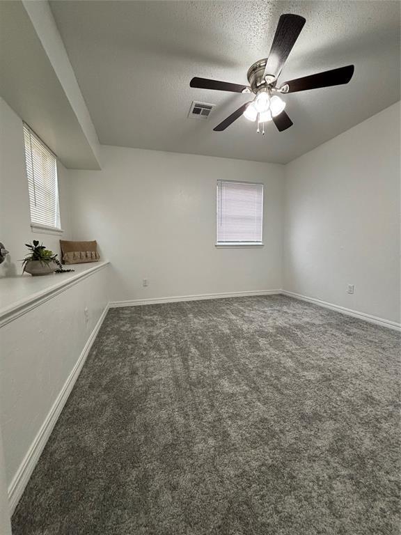 5213 Lombardy Ln, Oklahoma City, OK 73112 - carpeted empty room with healthy amount of natural light, a textured ceiling, a ceiling fan, and baseboards