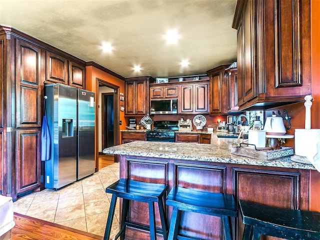 kitchen with stainless steel appliances, light stone countertops, light tile patterned floors, and a peninsula