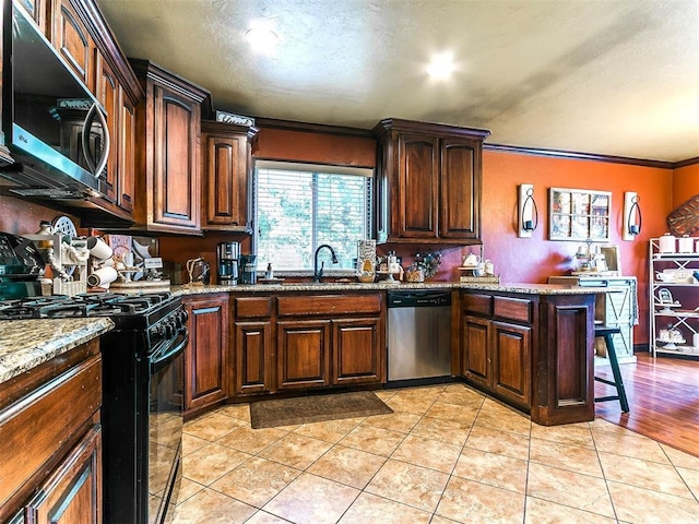 kitchen featuring crown molding, a peninsula, stone countertops, a sink, and stainless steel appliances