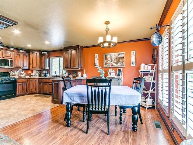 dining room featuring visible vents, a notable chandelier, ornamental molding, and light wood finished floors