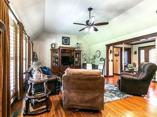 living room with ceiling fan, wood finished floors, and vaulted ceiling