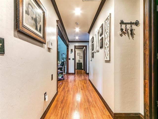 hall featuring crown molding, a textured wall, and wood finished floors