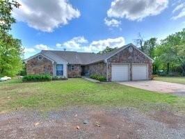 ranch-style home with an attached garage, a front lawn, driveway, and stone siding