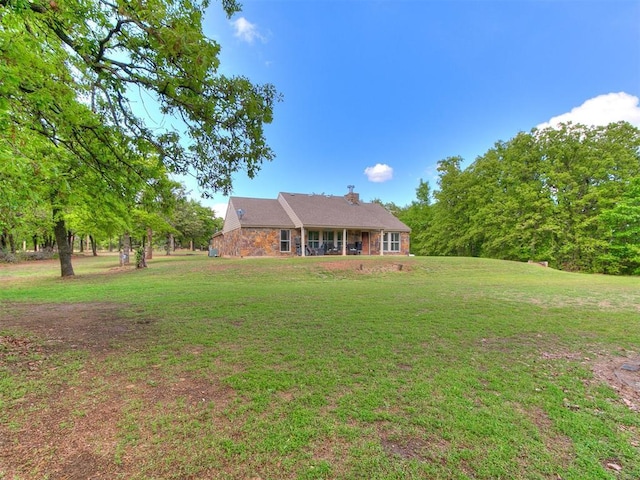 view of front of home featuring a chimney, stone siding, and a front lawn