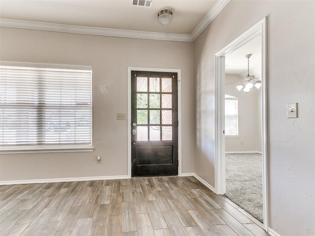 entryway featuring crown molding, ceiling fan, baseboards, wood finished floors, and visible vents