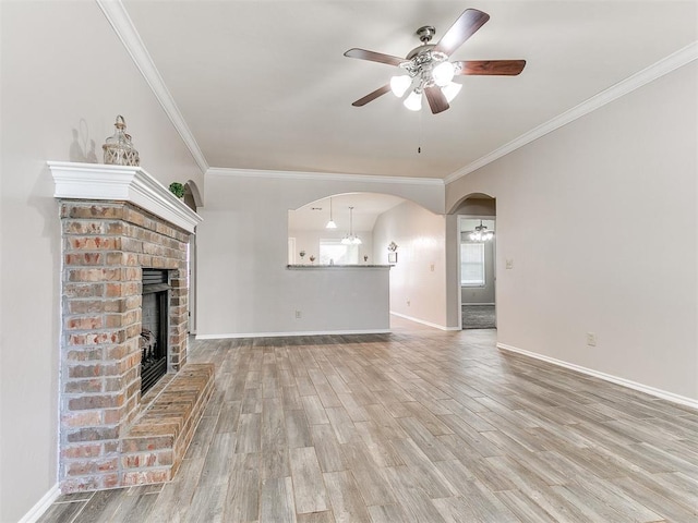 unfurnished living room with crown molding, a fireplace, a ceiling fan, baseboards, and wood finished floors
