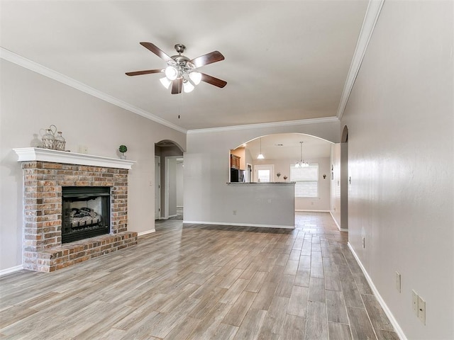 unfurnished living room with baseboards, arched walkways, ceiling fan, and wood finished floors