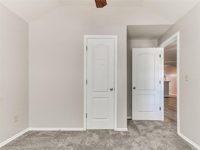 unfurnished bedroom with carpet floors, baseboards, and vaulted ceiling