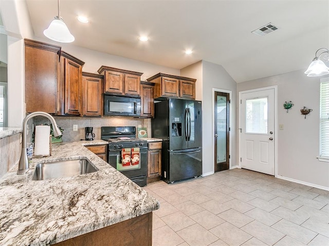 kitchen with brown cabinetry, visible vents, tasteful backsplash, a sink, and black appliances