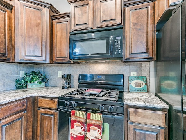 kitchen with backsplash, black appliances, and light stone countertops