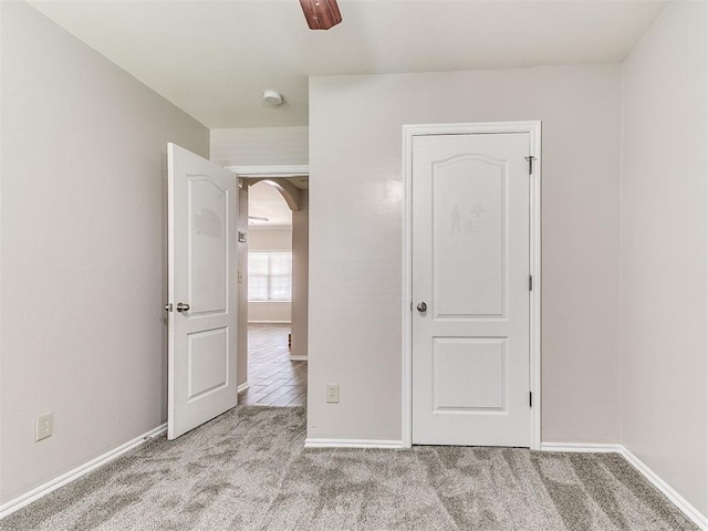 carpeted spare room featuring baseboards and arched walkways
