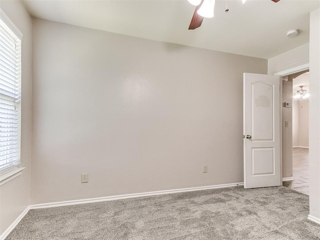 carpeted spare room with baseboards, ceiling fan, and a healthy amount of sunlight