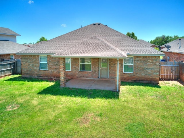 rear view of property featuring roof with shingles, a lawn, a fenced backyard, and brick siding