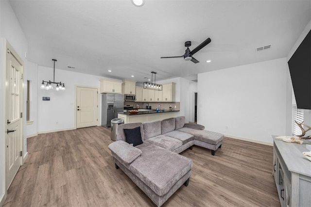 living room featuring visible vents, recessed lighting, light wood-style flooring, and ceiling fan with notable chandelier