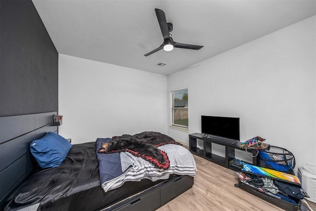 bedroom with a ceiling fan, visible vents, and wood finished floors