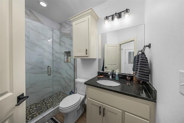bathroom featuring a marble finish shower, toilet, and vanity
