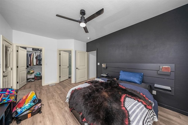 bedroom featuring wood finished floors, a closet, a ceiling fan, and baseboards