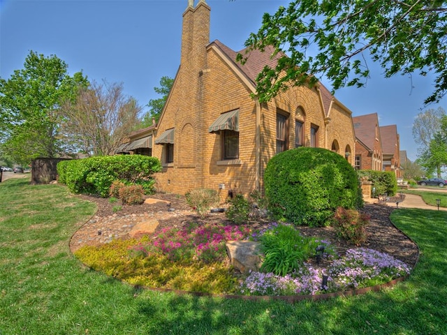 view of side of property featuring a yard, brick siding, and a chimney