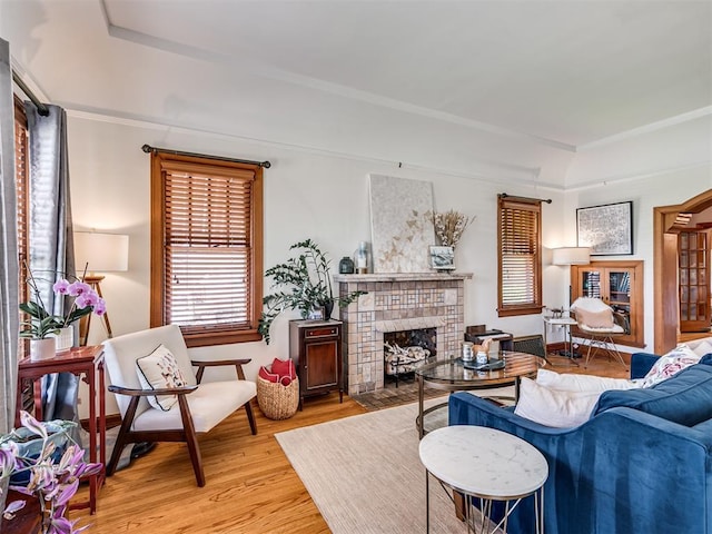 living area featuring a tiled fireplace, light wood-style flooring, and baseboards