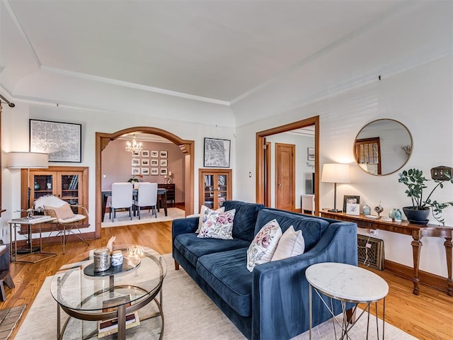living area featuring arched walkways, baseboards, wood finished floors, and a raised ceiling
