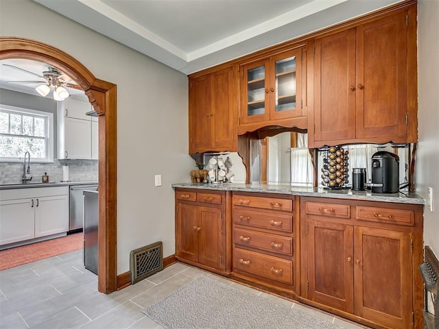 kitchen featuring visible vents, a sink, decorative backsplash, and brown cabinetry