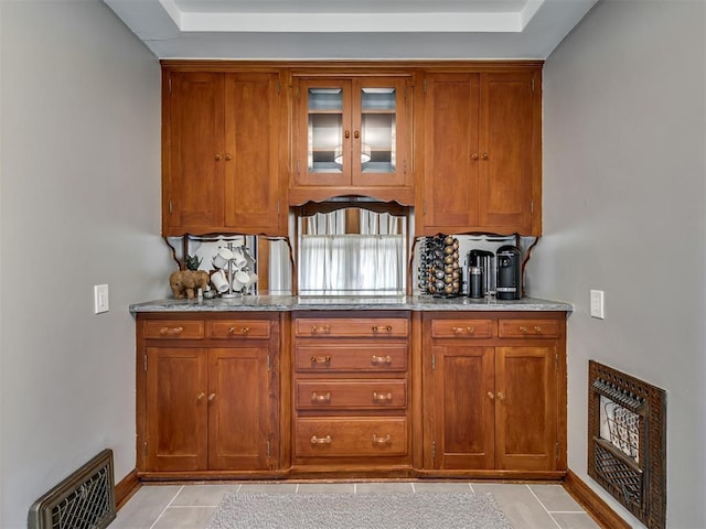 bar featuring a raised ceiling, baseboards, decorative backsplash, light tile patterned floors, and visible vents