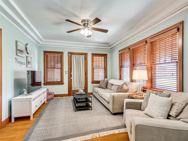 living area with baseboards, a ceiling fan, and light wood-style flooring